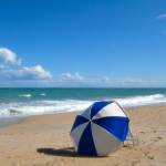 A parasol and beach chair sit on the sand near the Atlantic Ocean