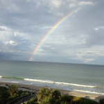 A rainbow over the Atlantic Ocean with frothy waves coming ashore