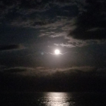 On a cloudy night, the moon shines brightly across the Atlantic Ocean.