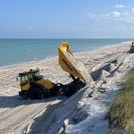 A small dump truck unloads sand onto the dunes.