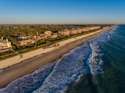 Aerial view along the beach in Orchid bathed in low sunlight showing waves and the Town's ten waterfront condominiums. 