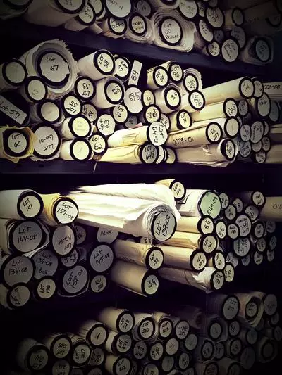 Stack of rolled up building plans in a vertical shelving unit numbered by lot