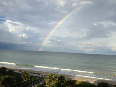 A rainbow over the Atlantic Ocean with frothy waves coming ashore