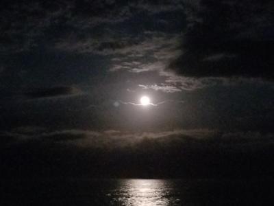 On a cloudy night, the moon shines brightly across the Atlantic Ocean.