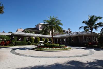 A roundabout in front of the beach club with in its center a palm tree surrounded by floral bushes